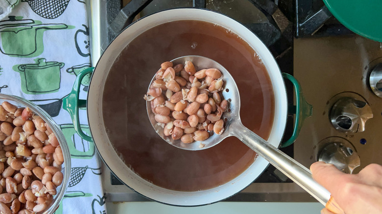 Removing beans with slotted spoon from pot