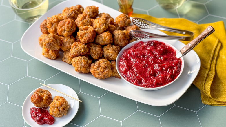 Classic sausage balls with cranberry mustard on serving platter with tongs and spoon