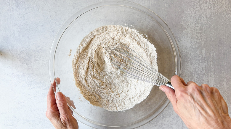 Whisking together dry ingredients for classic sausage balls in glass bowl