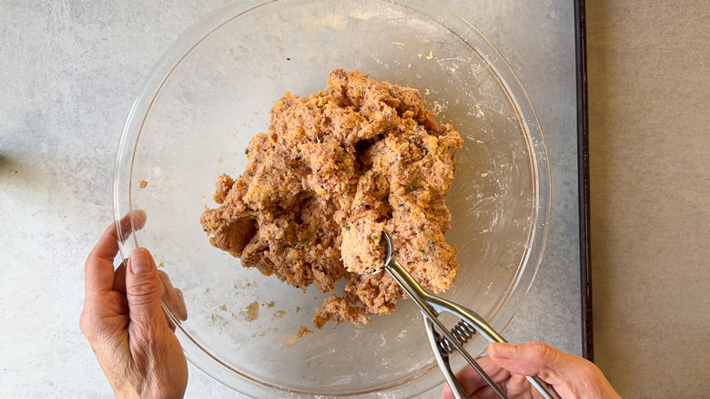 Scooping classic sausage ball mixture in glass bowl