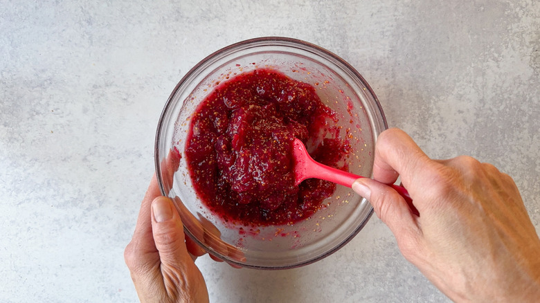 Mixing cranberry mustard in glass bowl with rubber spatula