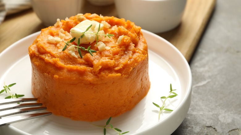 buttered sweet potato mash with herbs on a white plate