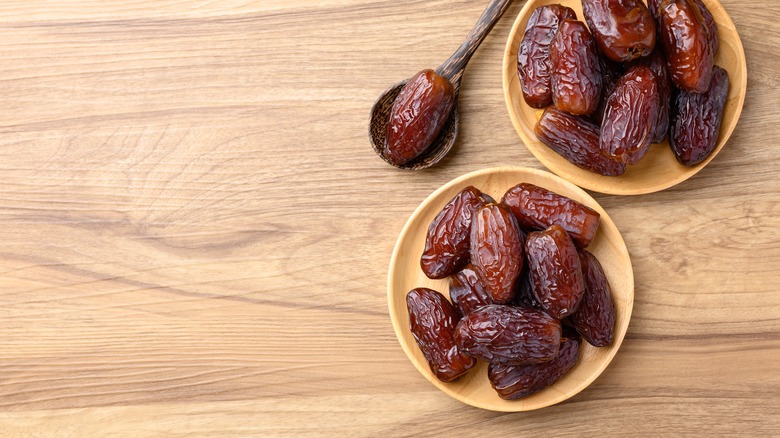 Medjool dates on two wooden plates on wooden table