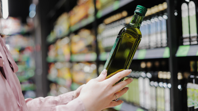 Woman choosing olive oil bottle