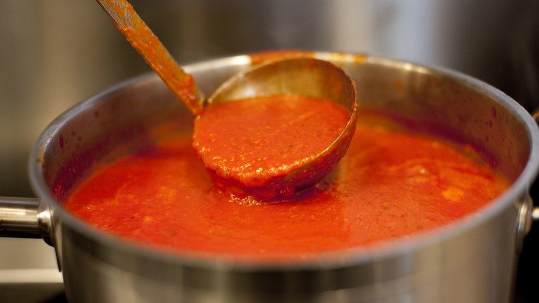 Marinara sauce simmering in a pot with a ladle