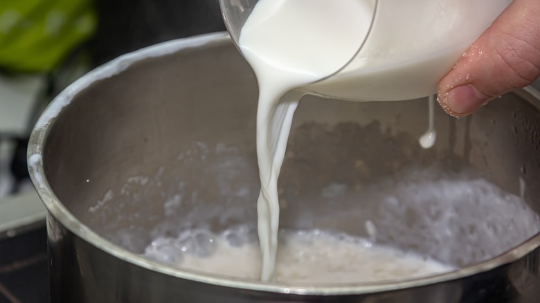 pouring milk into a pot to cook pasta