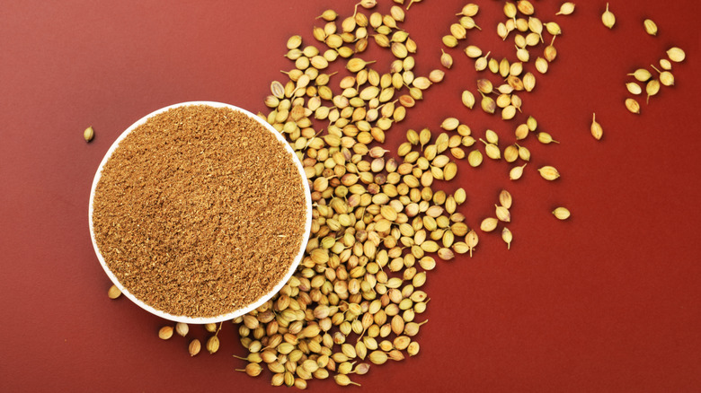 Coriander seeds on a table and ground coriander in a bowl