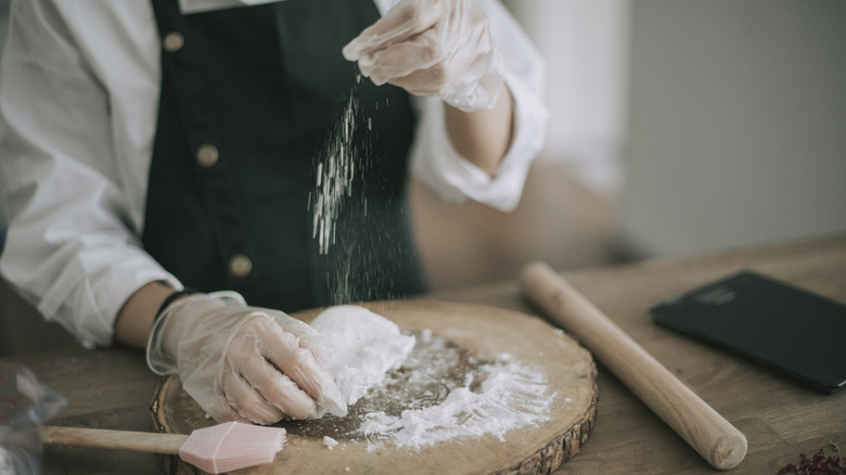 A chef sprinkles starch on some dough.