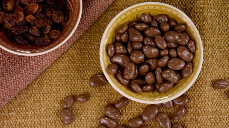 Chocolate-covered raisins next to raisin bowl