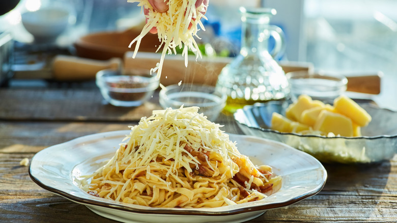 Sprinkling cheese onto pasta dish at a restaurant