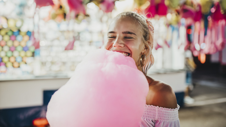 A girl eats cotton candy at a carnival