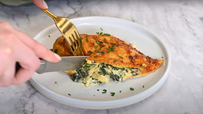 Chicken breast stuffed with cream cheese mixture being cut open by fork and knife