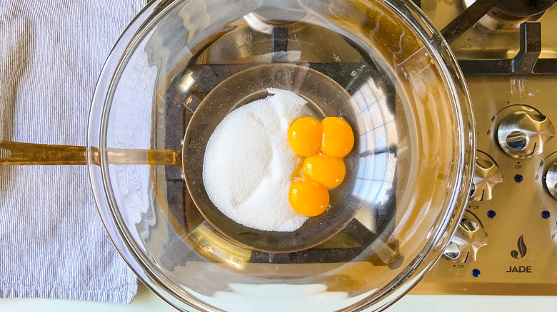 Sugar and yolks in bowl over water bath on stove