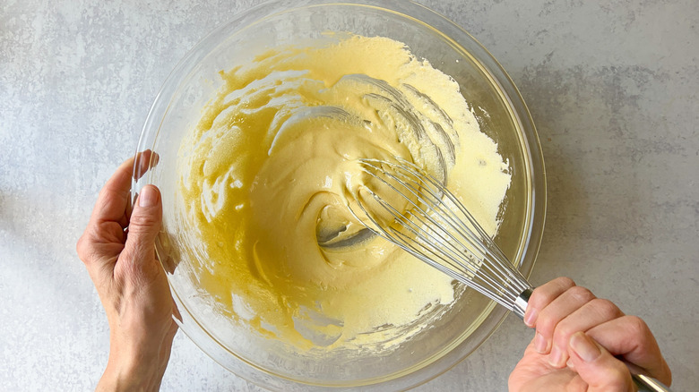 hand whisking yolks and sugar in bowl