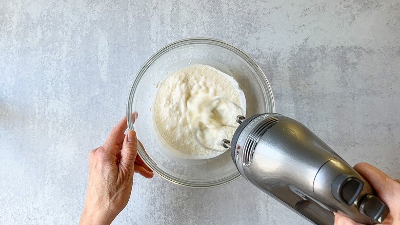 whipping heavy cream in bowl with hand mixer
