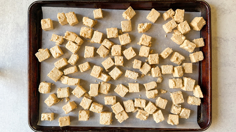 Marinated tofu cubes on parchment-lined baking sheet