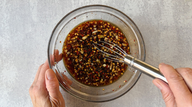 Whisking sticky sesame tofu sauce ingredients in glass bowl