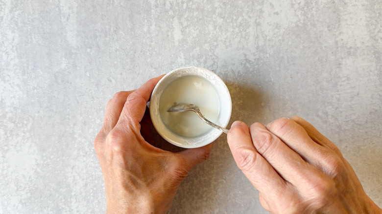 Mixing cornstarch with water in small ramekin with spoon