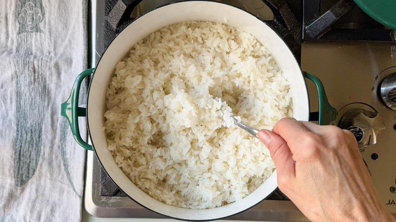 Fluffing rice in pot on stovetop with a fork