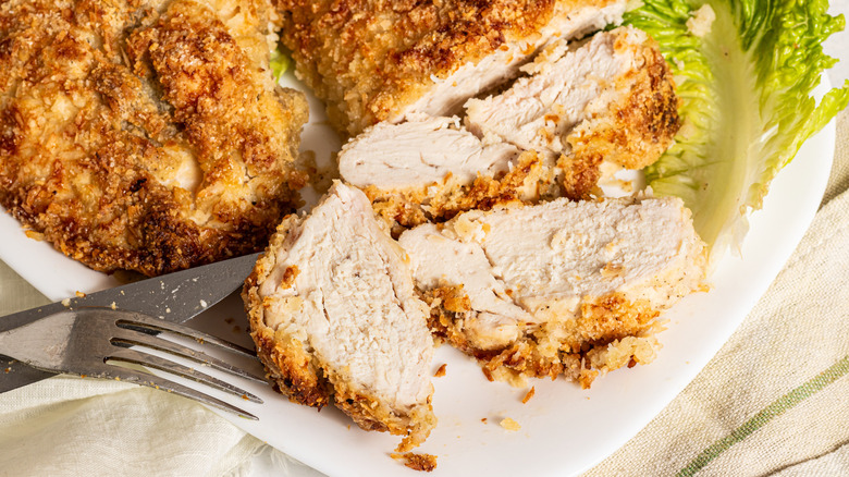 Close up shot of a sliced crispy coconut baked chicken breast on a plate