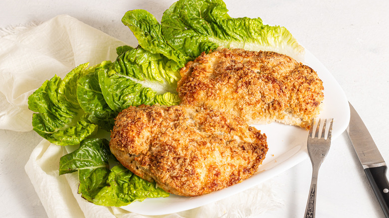 Two crispy coconut baked chicken breasts on a plate with lettuce
