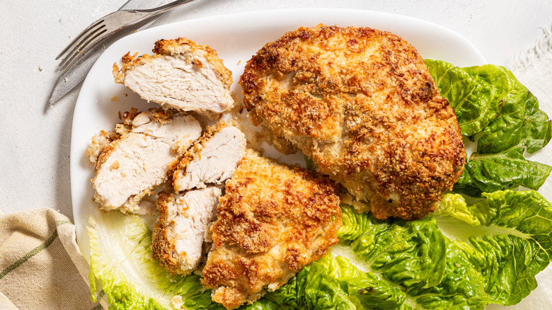 Slices of crispy coconut baked chicken breasts on a bed of lettuce