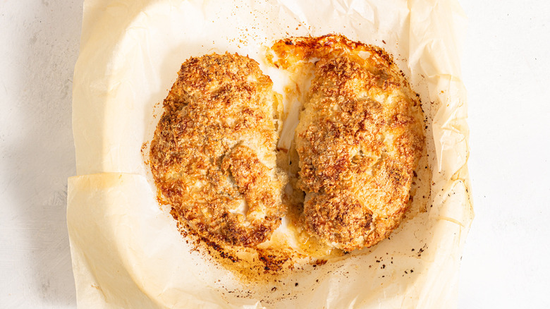 Baked coconut chicken breasts on a parchment lined baking dish