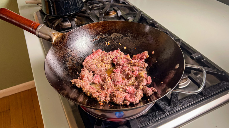 Ground beef cooking in wok on stove top