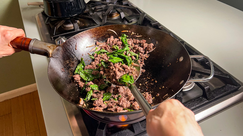 Crispy beef with basil leaves in wok