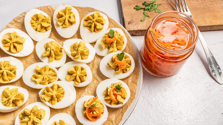 Topping off deviled eggs with pickled carrots and fresh cilantro leaves