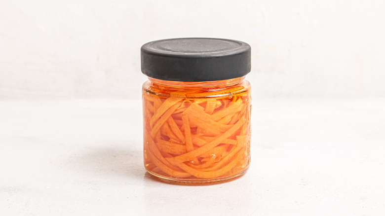 Jar filled with stripes of carrots in a marinade