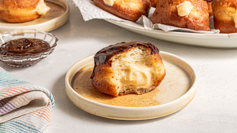 Custard-filled Boston cream donut with a bite off on a plate.