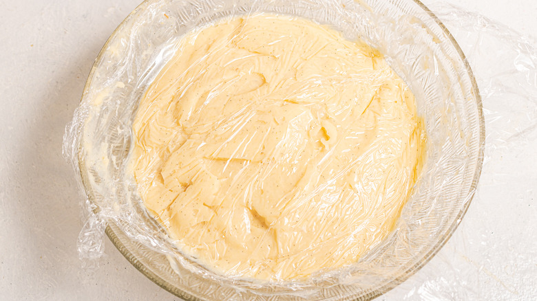 Pastry cream covered with plastic in a glass bowl