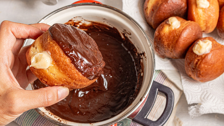 Dipping donut in chocolate sauce