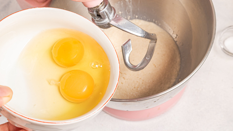 Adding two eggs to a mixer bowl