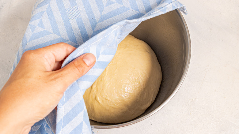 Covering dough in a bowl with a towel