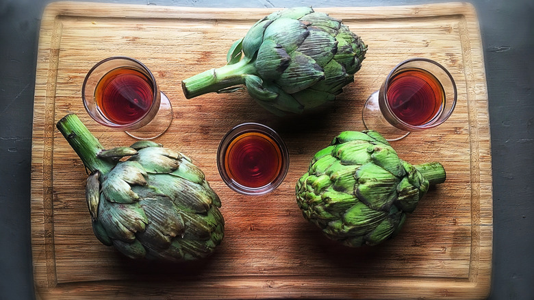 Cynar in glasses and artichokes on a wooden board