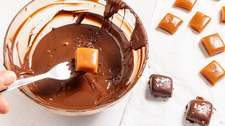 Dipping caramels into melted chocolate