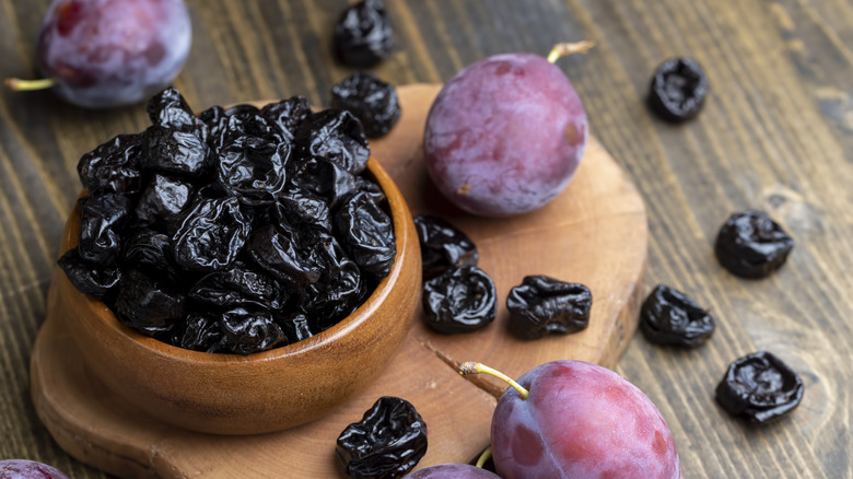 Bowl of prunes next to plums