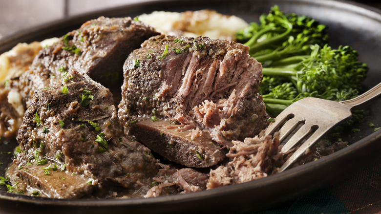 Fork pulling braised short ribs in a plate