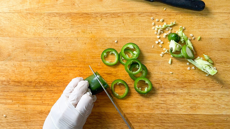 Slicing jalapeño rings using latex gloves on cutting board
