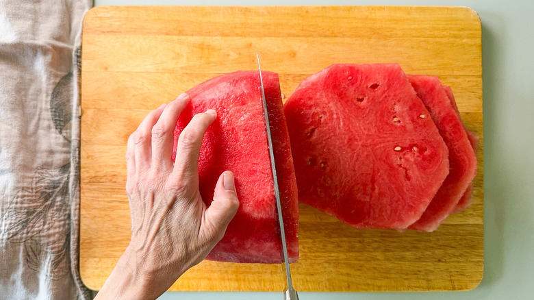 Cutting watermelon without rind into slices on cutting board