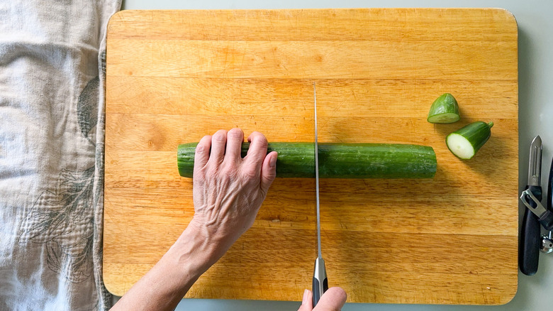 Trimming ends and cutting an English cucumber in half on cutting board