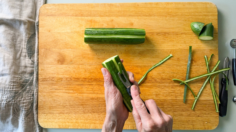 Scoring English cucumber with channel knife on cutting board