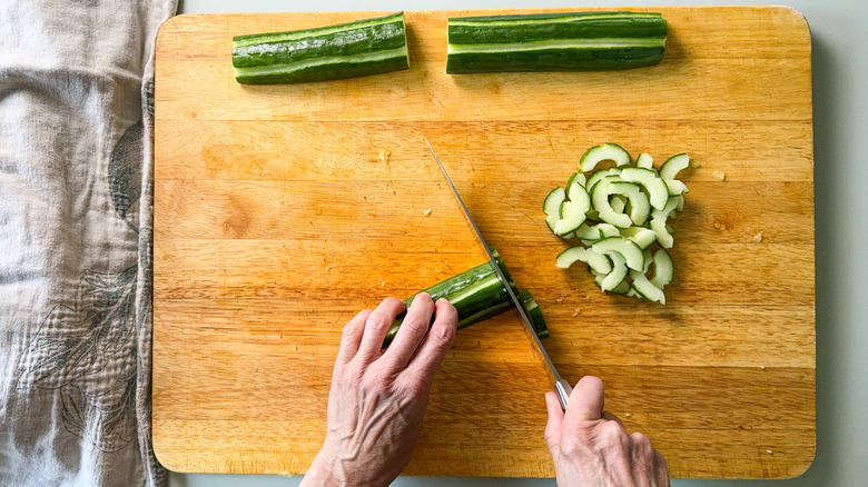 Slicing scored English cucumber on cutting board
