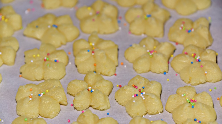 Sprinkles on top of raw cookies on a baking sheet