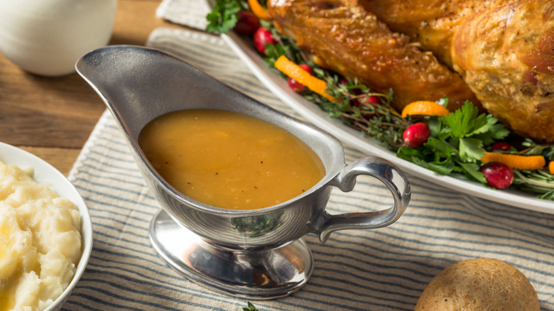 Gravy in a boat next to roast turkey