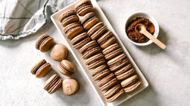 Delicate, decadent chocolate macarons on platter and table