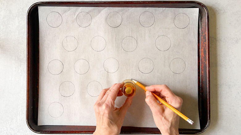 Tracing circles for macarons on parchment paper with pencil