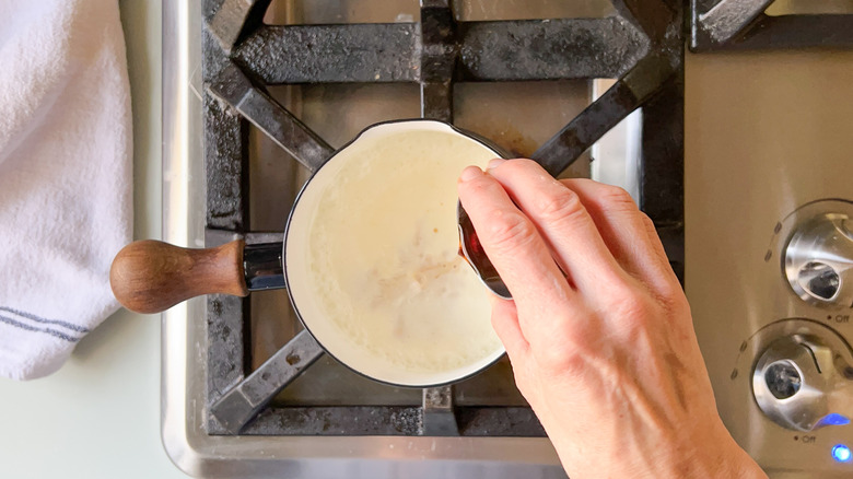 Pouring vanilla into heavy cream in sauce pan